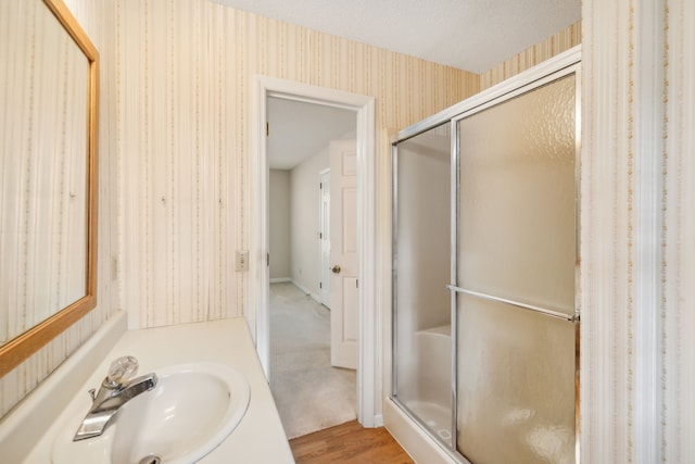 bathroom with hardwood / wood-style floors, a shower with shower door, vanity, and a textured ceiling