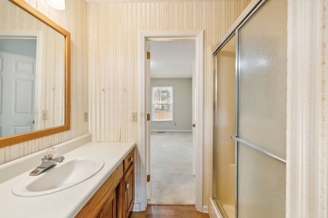 bathroom with walk in shower, vanity, and hardwood / wood-style flooring