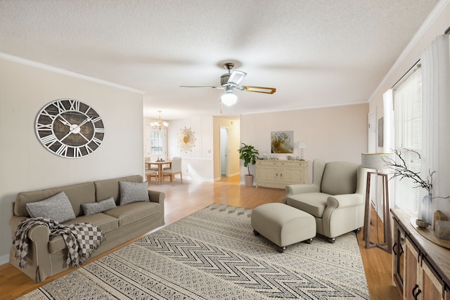 living room with ceiling fan with notable chandelier, light hardwood / wood-style flooring, a textured ceiling, and crown molding