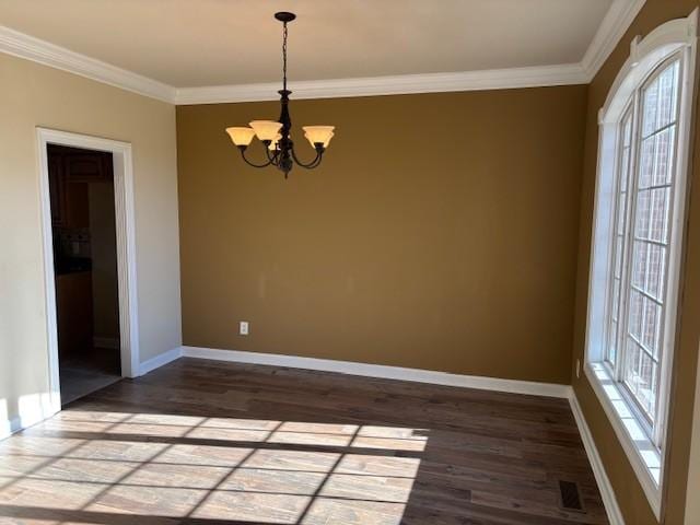 empty room featuring a chandelier, dark hardwood / wood-style floors, and crown molding