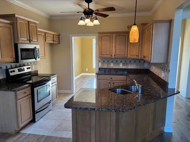 kitchen featuring decorative backsplash, stainless steel appliances, crown molding, sink, and decorative light fixtures