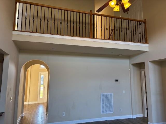 spare room with ceiling fan, a towering ceiling, and wood-type flooring