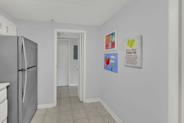 kitchen featuring stainless steel refrigerator, light tile patterned floors, and white cabinets