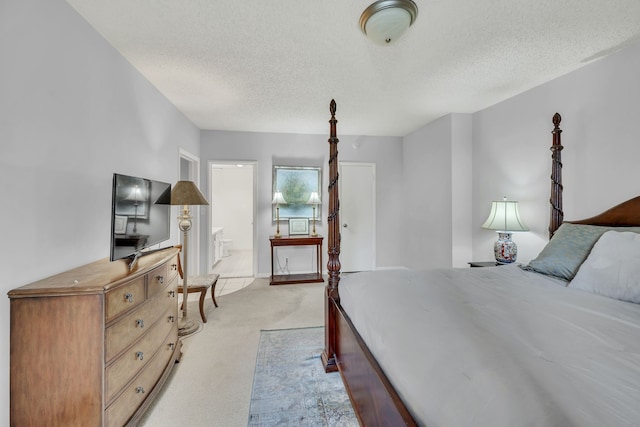 bedroom with a textured ceiling, light carpet, and ensuite bathroom