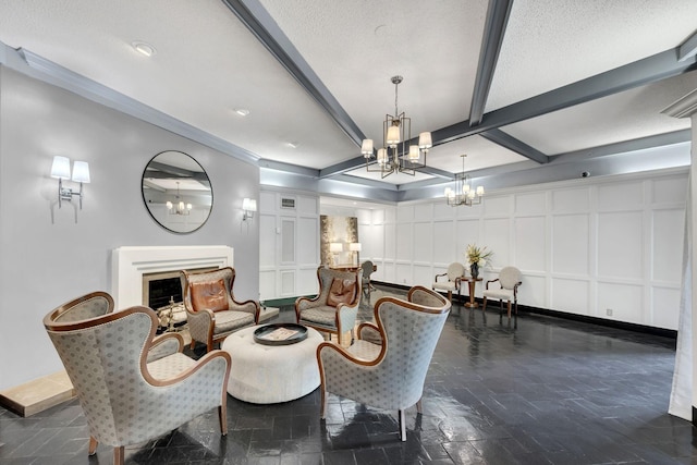living area with a chandelier, beam ceiling, a fireplace, a decorative wall, and baseboards
