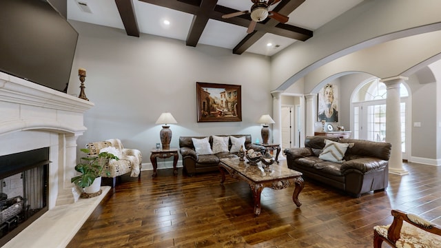 living room featuring beam ceiling, decorative columns, dark hardwood / wood-style floors, and ceiling fan