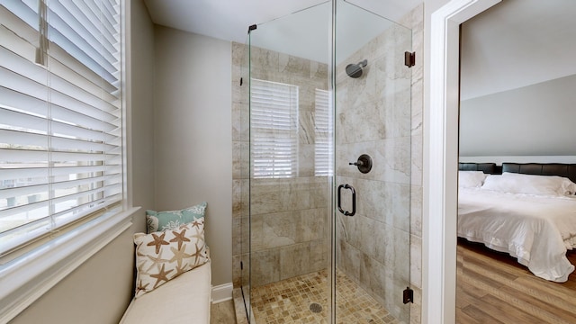 bathroom featuring wood-type flooring, a shower with shower door, and plenty of natural light