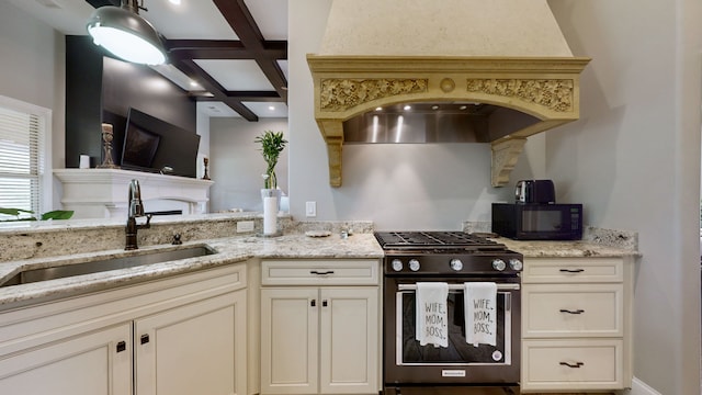 kitchen featuring light stone counters, beamed ceiling, stainless steel range with gas stovetop, sink, and coffered ceiling