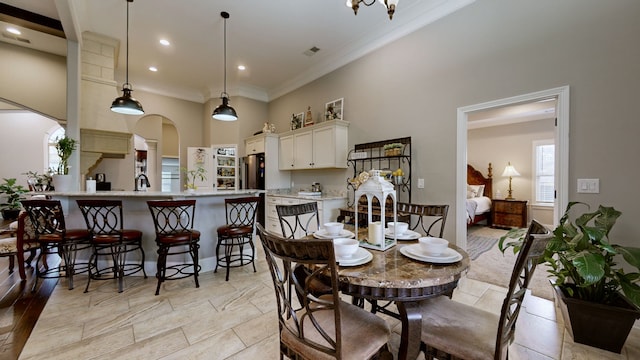 dining area with sink, crown molding, and a high ceiling