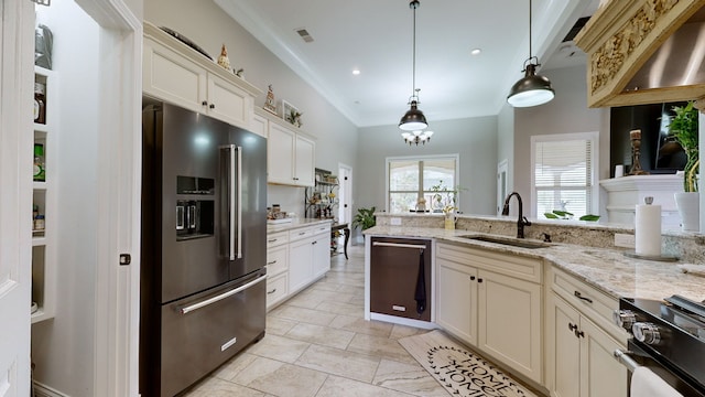 kitchen with cream cabinets, light stone counters, appliances with stainless steel finishes, pendant lighting, and sink