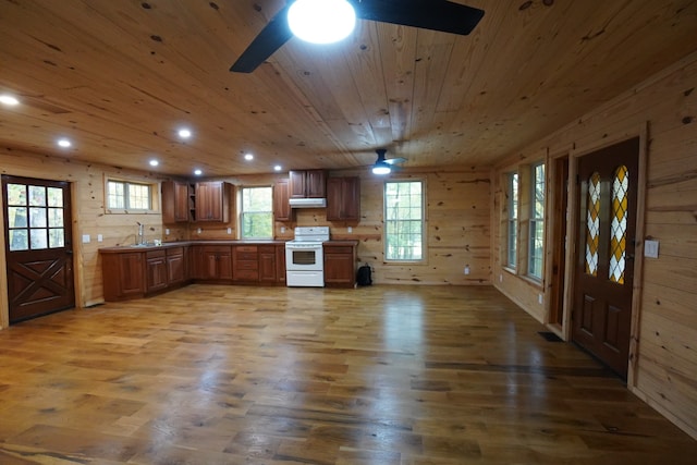 kitchen featuring wood walls, wood-type flooring, white range, and plenty of natural light