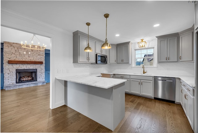 kitchen featuring appliances with stainless steel finishes, sink, kitchen peninsula, hardwood / wood-style floors, and a breakfast bar area