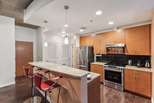 kitchen featuring appliances with stainless steel finishes, light stone countertops, decorative light fixtures, and dark hardwood / wood-style flooring