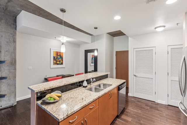 kitchen with dark hardwood / wood-style floors, an island with sink, stainless steel appliances, sink, and pendant lighting