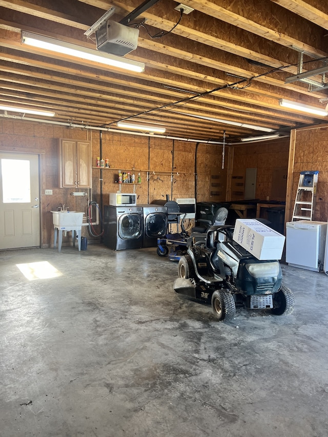 garage featuring sink, a garage door opener, and independent washer and dryer