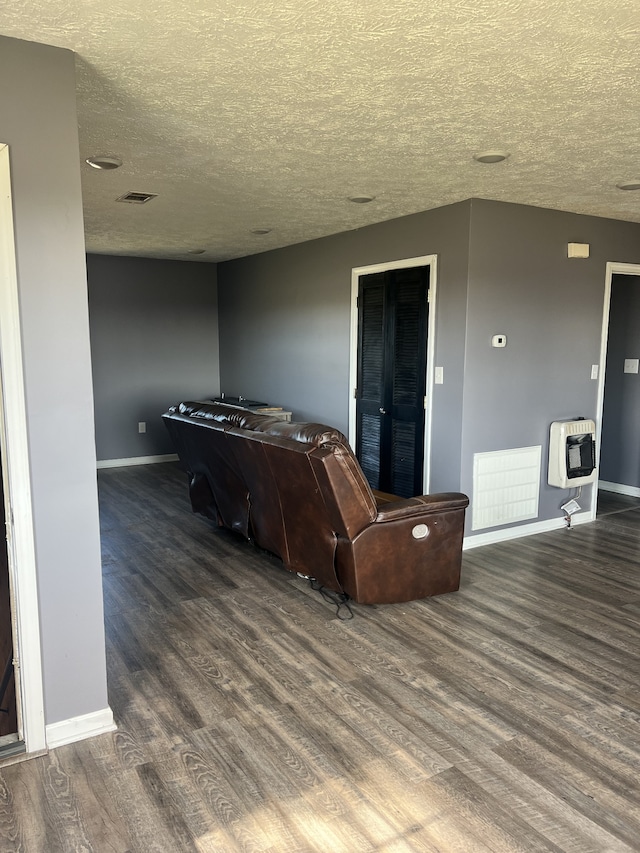 living room featuring dark hardwood / wood-style floors, a textured ceiling, and heating unit