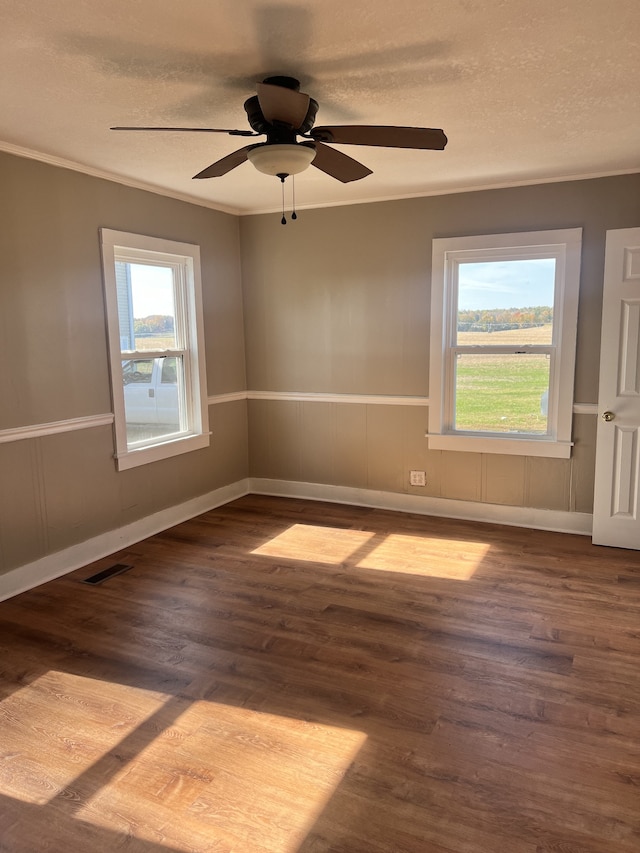 empty room with a textured ceiling, a healthy amount of sunlight, wood-type flooring, and ceiling fan