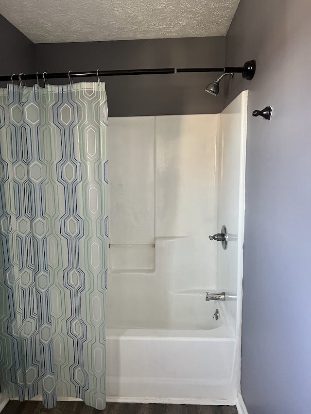 bathroom with shower / bath combo and a textured ceiling