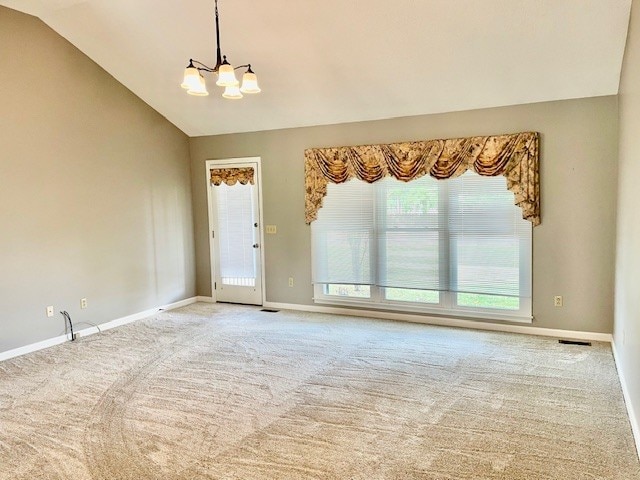 carpeted empty room featuring vaulted ceiling and a notable chandelier