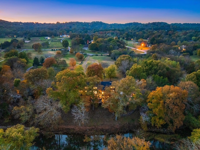 aerial view at dusk featuring a water view