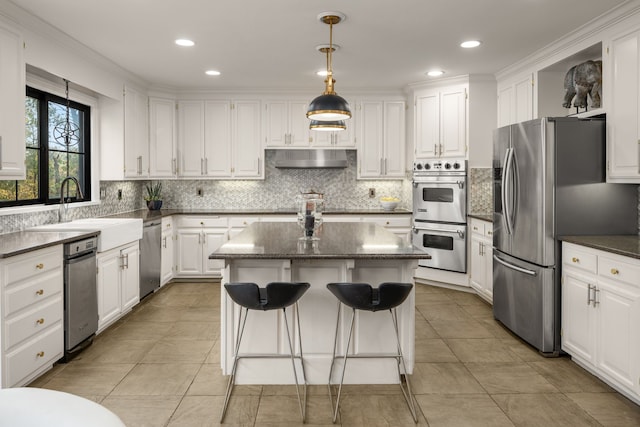 kitchen with white cabinetry, appliances with stainless steel finishes, a center island, and sink