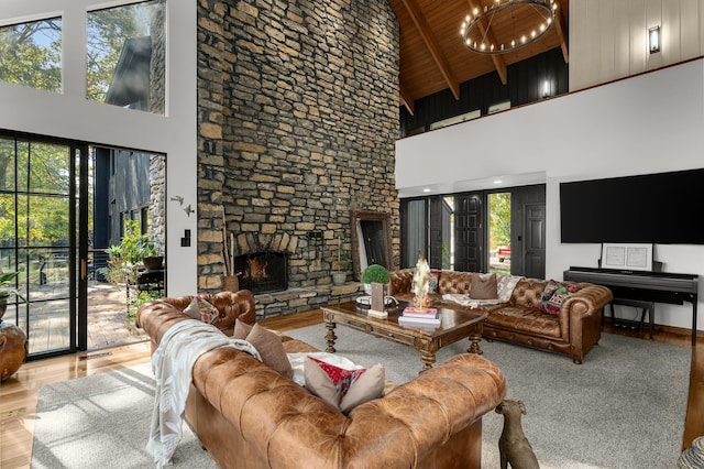 living room with a stone fireplace, beam ceiling, wooden ceiling, light wood-type flooring, and high vaulted ceiling