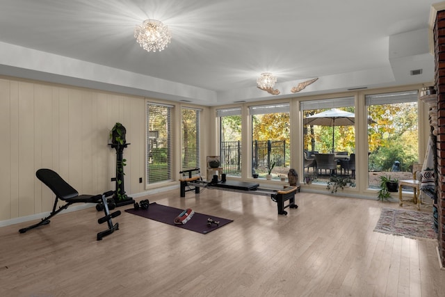 workout room with wood walls, hardwood / wood-style floors, and a chandelier