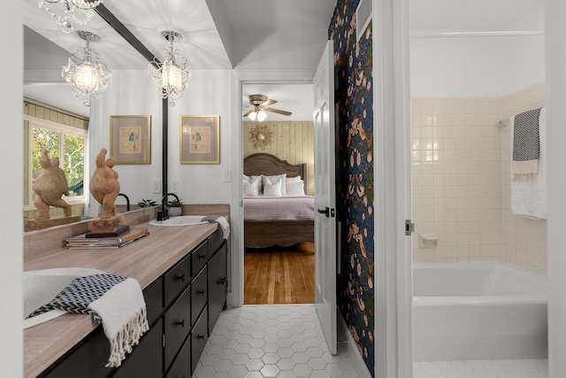 bathroom featuring vanity, ceiling fan with notable chandelier, a tub to relax in, and tile patterned flooring