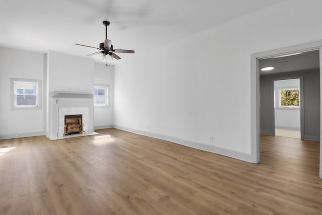 unfurnished living room with a tile fireplace, light hardwood / wood-style floors, and ceiling fan