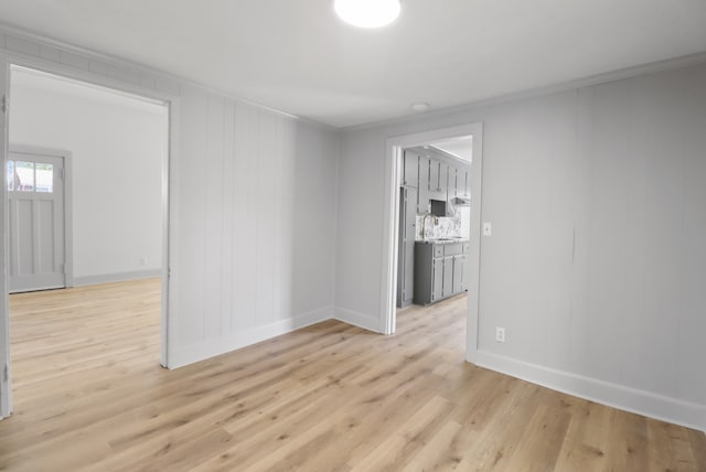 spare room featuring light hardwood / wood-style flooring, sink, and crown molding