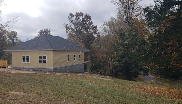 view of side of home featuring a lawn and roof with shingles