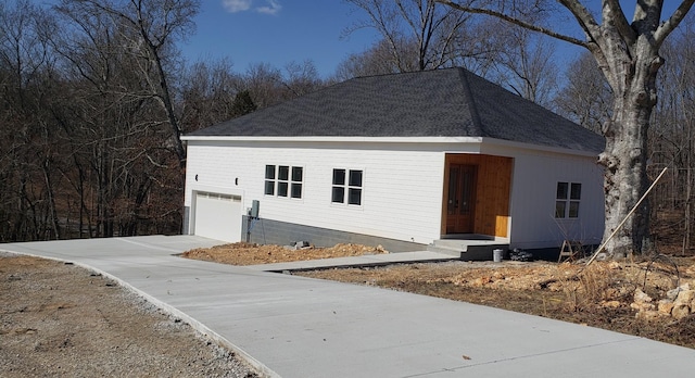 view of front of property with a shingled roof and concrete driveway