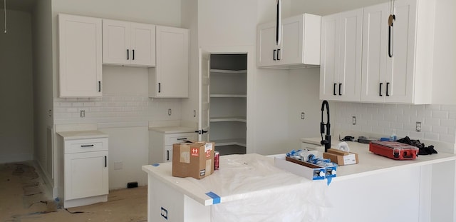 kitchen featuring backsplash, white cabinets, and a peninsula