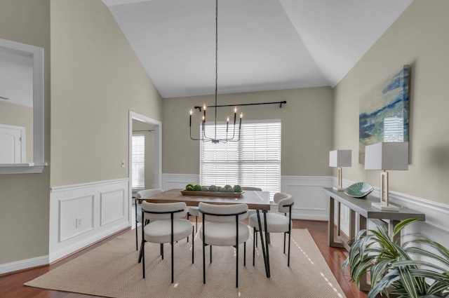 dining space with wood-type flooring, lofted ceiling, and a notable chandelier