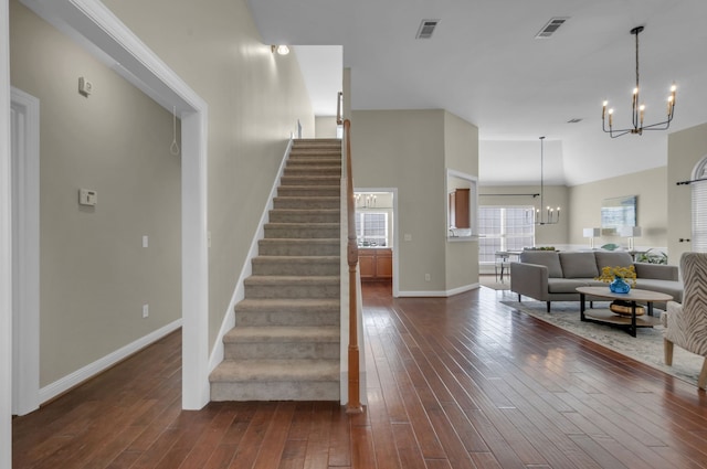 stairs featuring wood-type flooring and an inviting chandelier