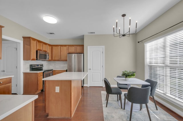 kitchen featuring pendant lighting, stainless steel appliances, a kitchen island, and a wealth of natural light