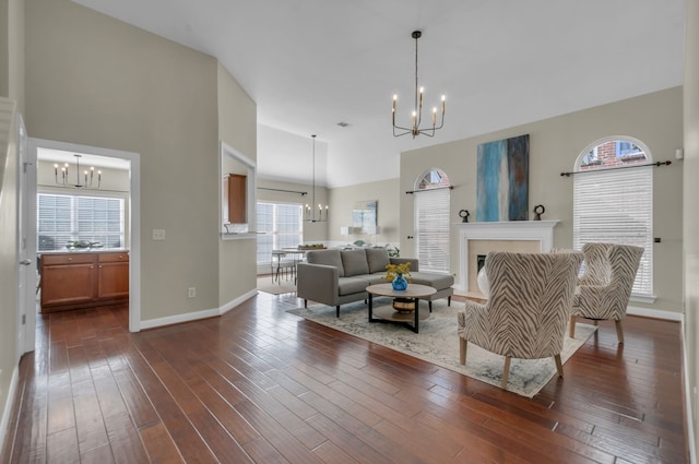 living room with dark hardwood / wood-style flooring, high vaulted ceiling, and a notable chandelier