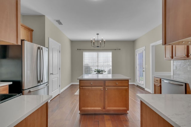 kitchen featuring backsplash, light hardwood / wood-style flooring, appliances with stainless steel finishes, decorative light fixtures, and a chandelier