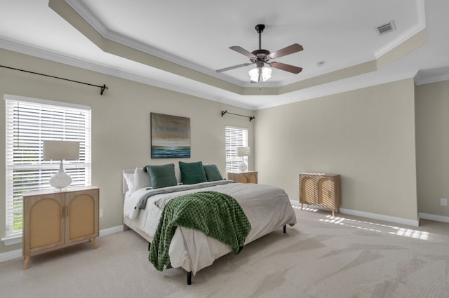 carpeted bedroom with ceiling fan, ornamental molding, and a tray ceiling