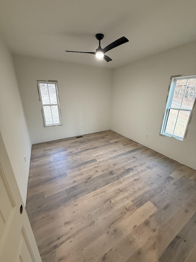 empty room featuring ceiling fan, a healthy amount of sunlight, and wood-type flooring