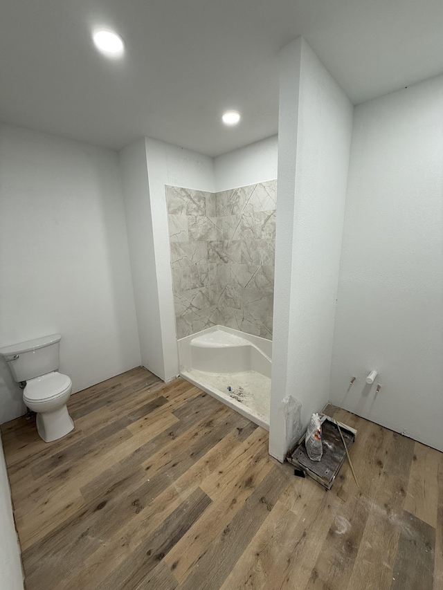 bathroom with hardwood / wood-style floors, toilet, and tile walls