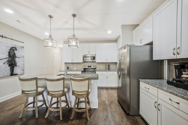 kitchen with decorative backsplash, white cabinets, an island with sink, dark wood-type flooring, and stainless steel appliances