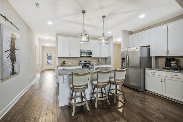 kitchen with a kitchen island with sink, dark wood-type flooring, white cabinets, and stainless steel appliances