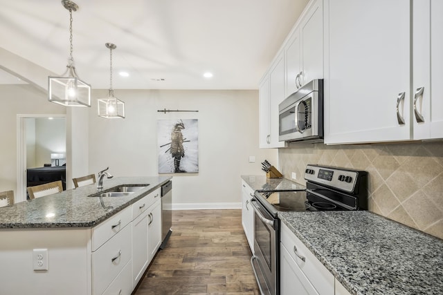 kitchen featuring appliances with stainless steel finishes, white cabinetry, a kitchen island with sink, dark wood-type flooring, and sink