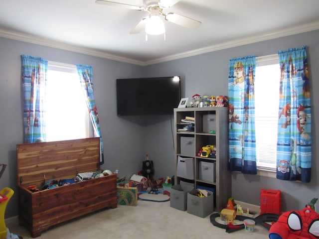 rec room with a wealth of natural light, crown molding, carpet floors, and ceiling fan