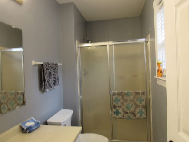 bathroom featuring toilet, a shower with shower door, and vanity