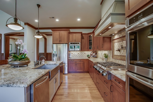 kitchen featuring pendant lighting, premium range hood, sink, tasteful backsplash, and stainless steel appliances