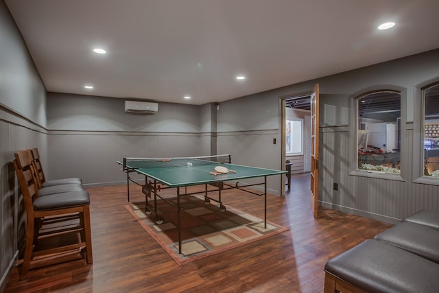 rec room featuring a wall mounted air conditioner and dark hardwood / wood-style floors