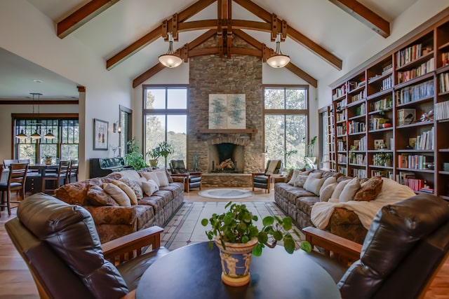 living room with beamed ceiling, a stone fireplace, and high vaulted ceiling