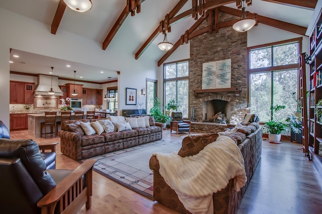 living room featuring hardwood / wood-style flooring, beam ceiling, a fireplace, and high vaulted ceiling